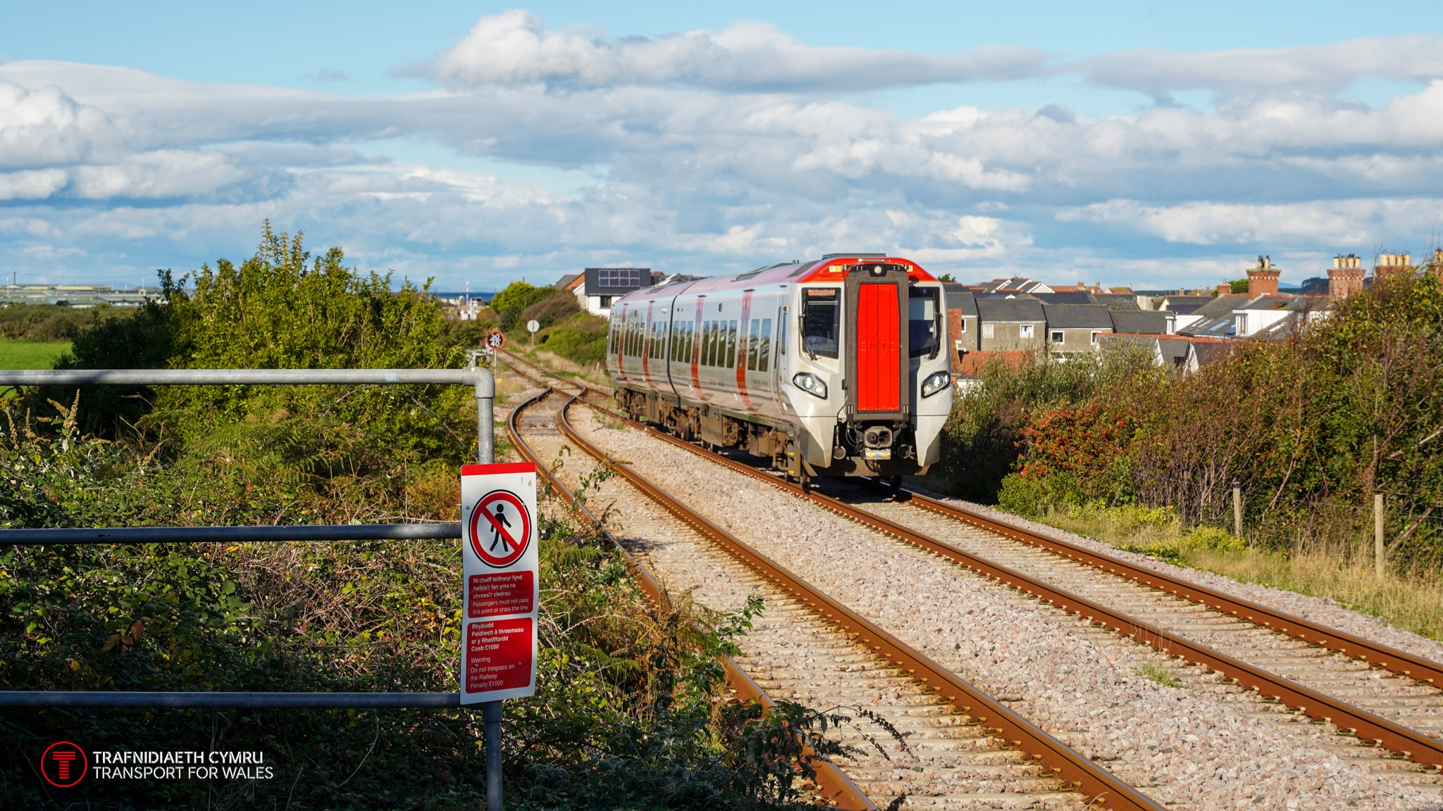 A passenger train running along a coastal railway line in Wales