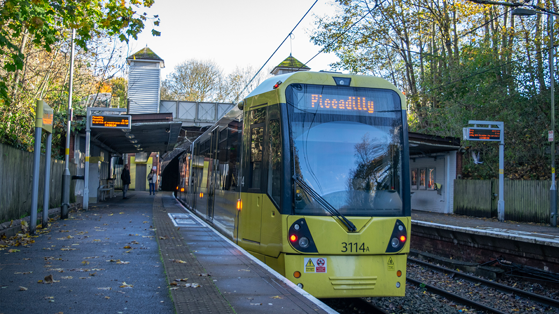 A Metrolink tram at a platform stop in Greater Manchester