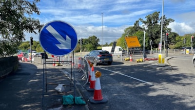 Roadworks with traffic cones and barriers on a busy urban road