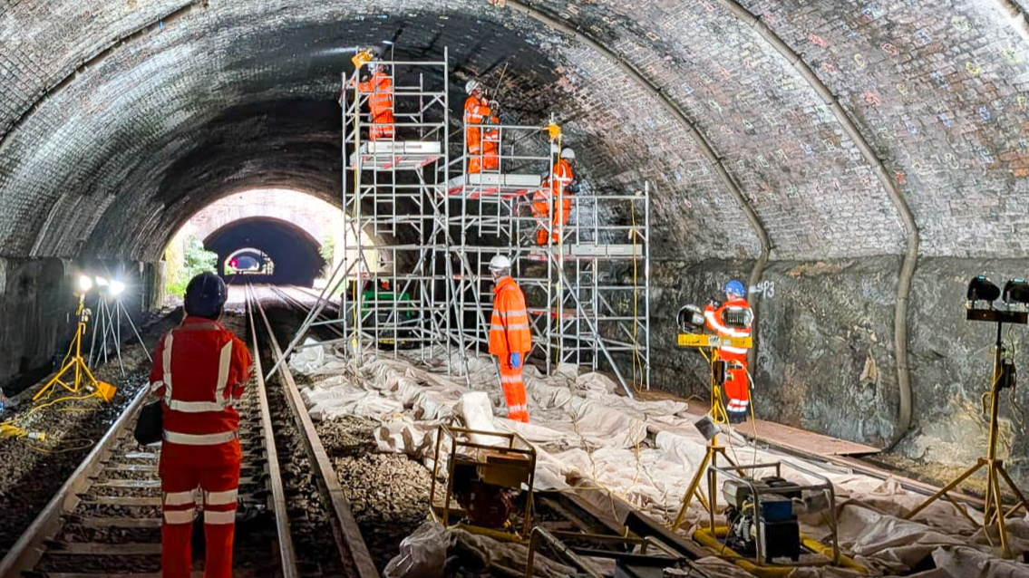 Engineers working inside a brick-lined Victorian railway tunnel