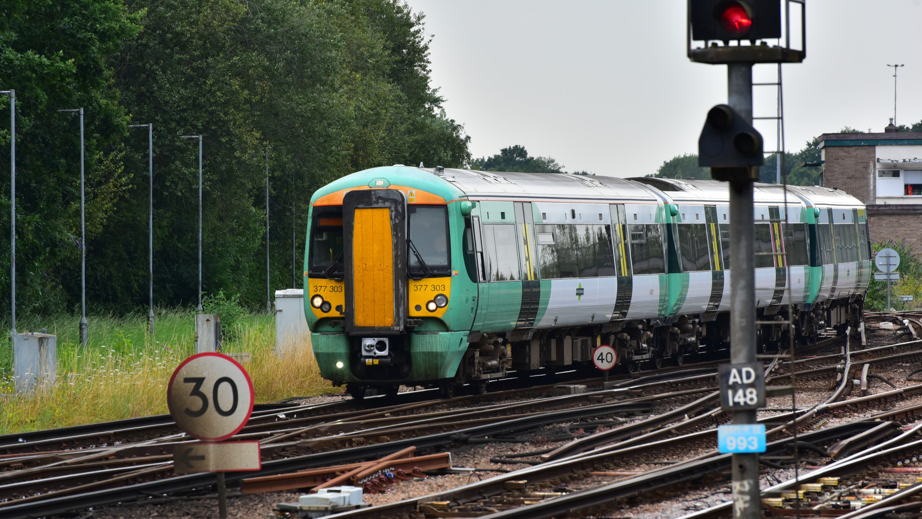 Engineers installing steel sheet piles into a railway embankment beside the track