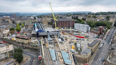 Engineers installing new railway track and overhead line masts during a station closure